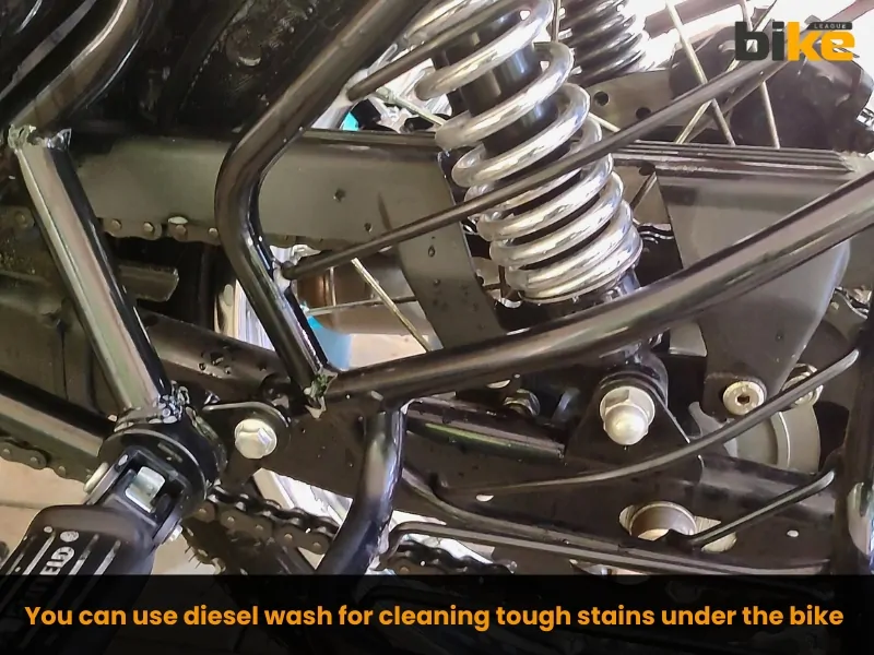 You can use diesel wash for cleaning tough stains under the bike only